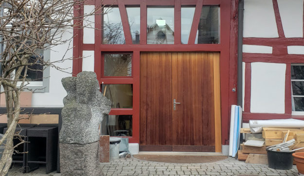 Mein Küchenatelier zeigt ein Bild von einer Eingangstür aus Holz in rot gerahmten Fenstern